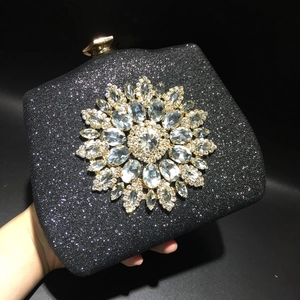 Detail of black glitter evening bag with crystal sunflower ornament and metal base