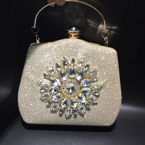 Detailed view of gold evening clutch featuring a large sparkling rhinestone flower design