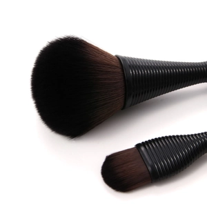 Close-up of two makeup brushes showing soft synthetic bristles and textured black handles