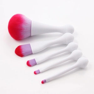Detail of 5 makeup brushes with white spiral handles and pink purple gradient bristles