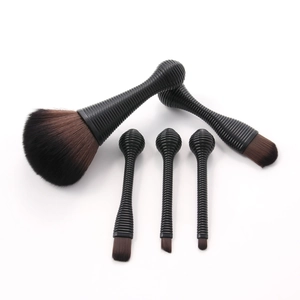 Detailed close-up of 5 portable makeup brushes with black spiral handles and gradient bristles