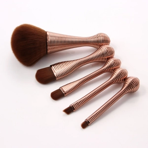 Detailed view of 5 rose gold spiral handle makeup brushes with soft brown bristles