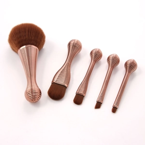 Flat lay of 5 makeup brushes with rose gold spiral handles and brown synthetic bristles