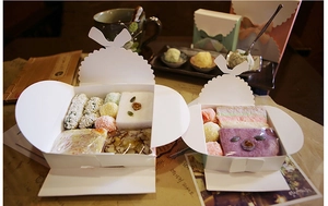 Détail d'une boîte cadeau en carton blanc avec nœud creux et assortiment de pâtisseries