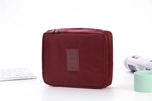 Close-up of burgundy travel toiletry bag featuring embossed airplane icon and Travel text