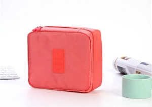 Detail of coral red nylon travel pouch with grid texture and embossed TRAVEL logo
