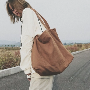 Brown canvas tote bag with large capacity shown in a casual outdoor style