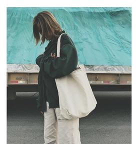 Detail view of off-white oversized canvas tote bag styled as a minimalist shoulder bag
