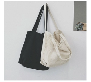 Minimalist canvas shoulder bags in black and cream hanging on a wall in a clean setting