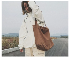 Brown oversized canvas tote bag shown in an outdoor lifestyle setting for casual wear