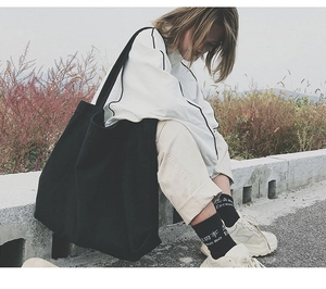 Outdoor lifestyle shot of a large black canvas tote bag in a casual setting