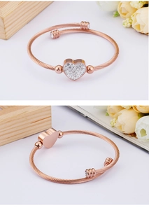 Detailed macro view of heart charm bracelet with rose gold woven wire and crystals