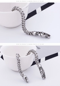 Detail of silver wheat chain bracelet with vintage floral engraved clasp on white decor