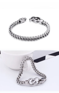 Detailed close-up of a silver stainless steel braided chain bracelet with an infinity clasp