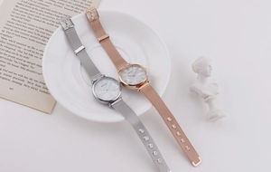 Detail of silver and rose gold mesh strap watches with marble pattern dials on a white plate