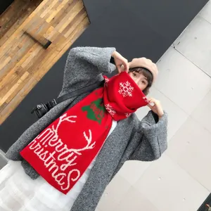 Macro shot of red Christmas knit scarf with white reindeer and Merry Christmas text
