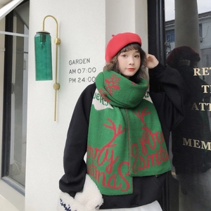 Close-up of green Christmas knitted scarf with reindeer pattern and Merry Christmas text