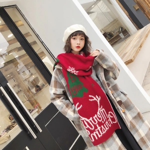 Detail of red knit scarf with green Christmas trees and Merry Christmas text pattern