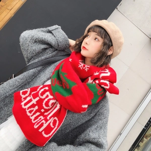 Detail of red knit scarf with white Christmas text and green tree patterns