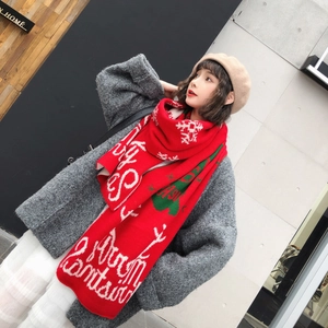 Detail shot of a red knitted winter scarf with white Christmas text and green snowflake patterns