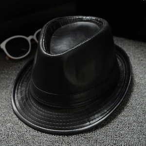 Classic black PU leather jazz fedora hat with sunglasses on a textured grey carpet