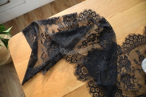 Close-up of black eyelash lace runner with floral patterns on a wooden table surface