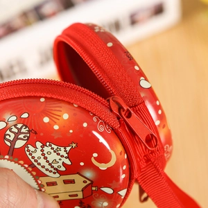 Close-up of red tinplate Christmas coin purse with snowy house and tree pattern