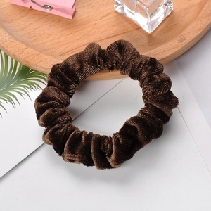 Detail of soft brown velvet scrunchie texture on a minimalist wooden tray display