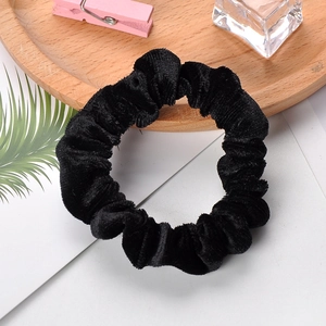 Detailed texture of a classic black velvet scrunchie on a decorative wooden tray