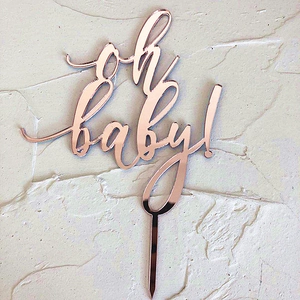 Detail of rose gold acrylic Oh Baby cake topper with a reflective mirror finish