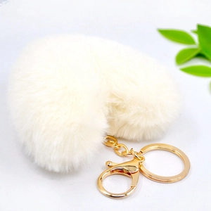 Close-up of a soft cream plush heart keychain with gold ring and lobster clasp detail