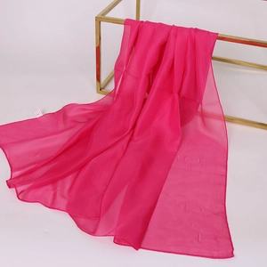 Sciarpa leggera in chiffon magenta su supporto dorato con un morbido drappeggio fluido