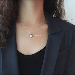 Detail of a minimalist S925 sterling silver heart necklace worn on a black blazer