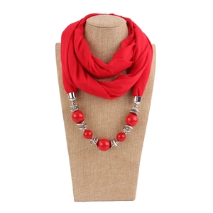 Detail of red beaded circle scarf necklace with silver accents on a textile bust display