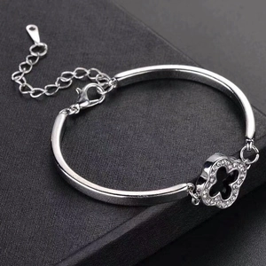 Detailed view of silver clover bracelet with sparkling zircons on black background
