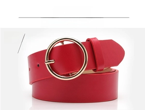 Detail view of fashion red belt with a polished gold round buckle and leather texture