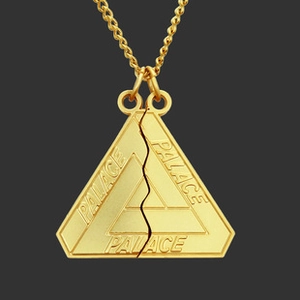 Macro shot of gold-plated triangle pendant featuring engraved Palace lettering detail