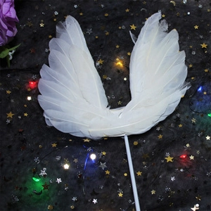 Close-up of a white feather wing cake topper on a dreamy starry background with LED lights