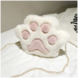 Detail of plush cat paw crossbody bag with gold chain strap on white bedding background