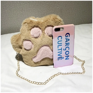 Close-up of plush cat paw crossbody bag with metal chain next to a phone for size reference