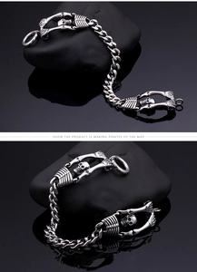 Macro shot of punk skeleton hands and thick steel chain bracelet on black stone