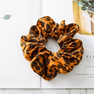 Close-up of leopard print satin scrunchie with soft silk texture on a magazine