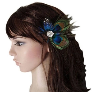 Detail of peacock feather hair clip with rhinestones worn by a model on white background