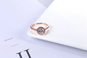 Close-up of rose gold halo engagement ring with round cubic zirconia and side stones