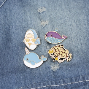Detaillierte Nahaufnahme von Wal- und Hai-Emaille-Pins auf blauem Denim-Hintergrund