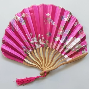 Detail of pink silk folding fan with floral patterns, bamboo ribs and matching tassel