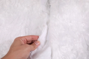 Detail of white plush Christmas tree skirt featuring secure hook and loop velcro closure