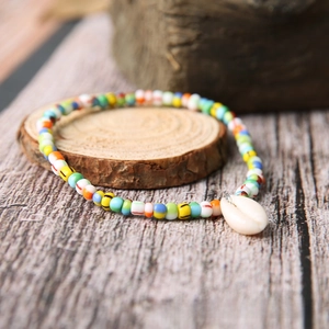 Close-up of colorful bohemian bead bracelet with a white natural shell charm on wood