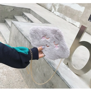 Close-up of fluffy grey cloud-shaped plush bag with embroidery and gold chain strap