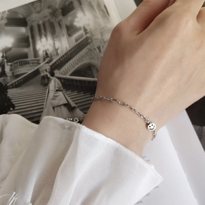 Detail of S925 sterling silver smile face pendant bracelet worn on a woman's wrist